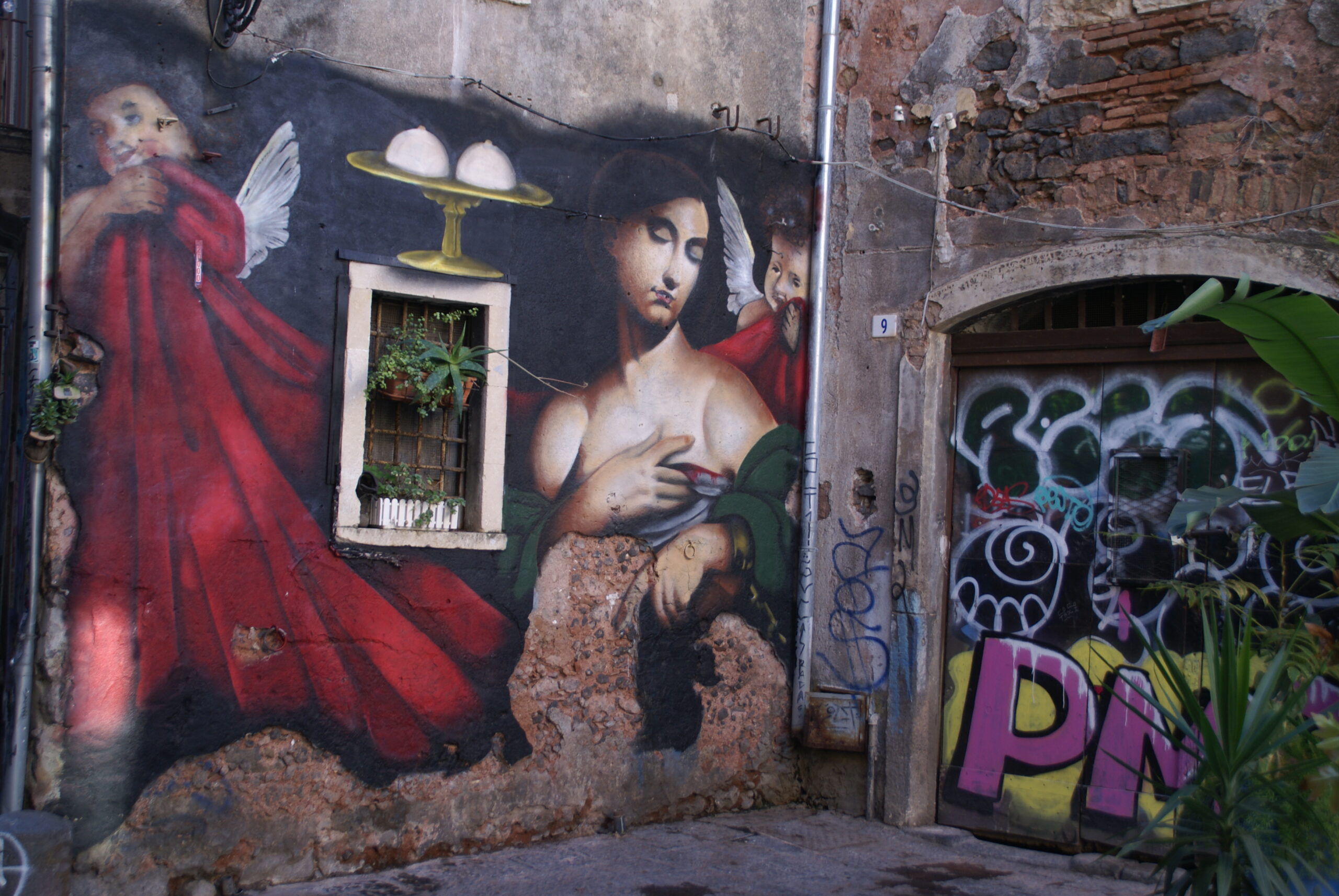 Murale con due volti stilizzati su un muro nel centro di Catania